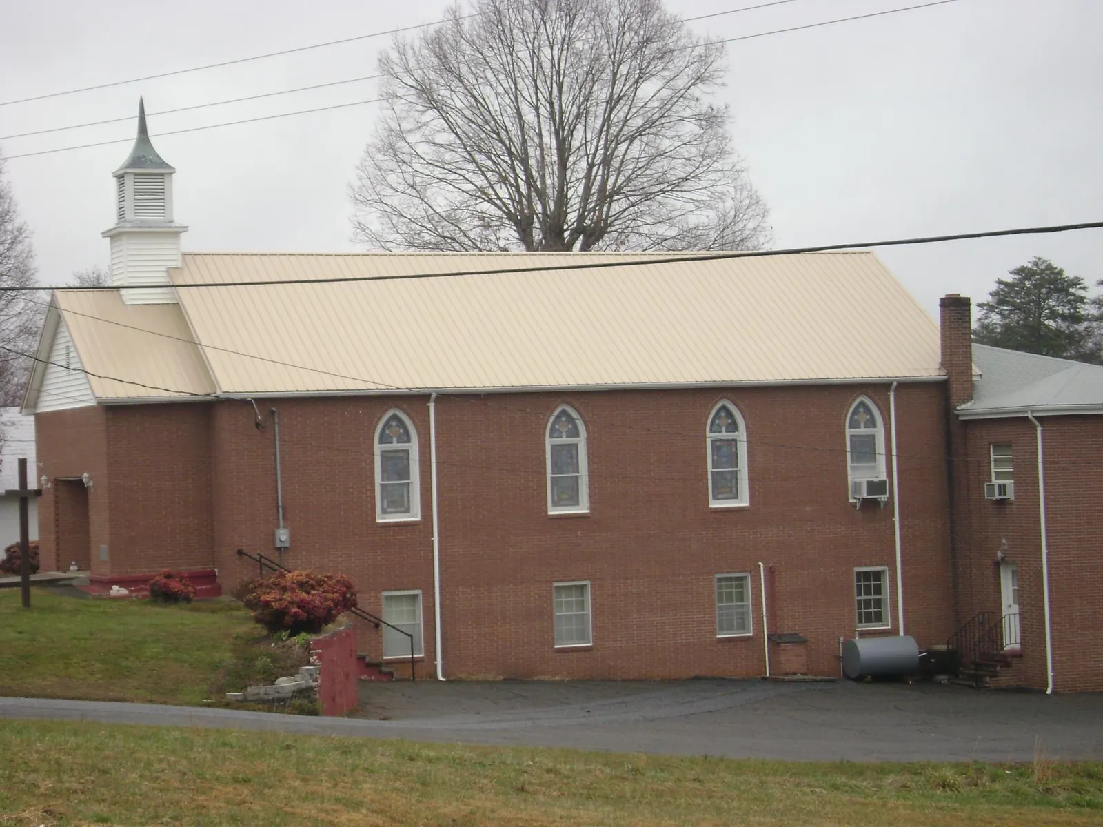 New tan metal roof on a brick church with a white steeple in Marysville
